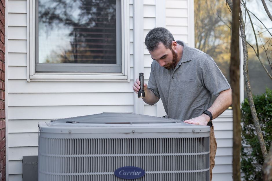 technician inspecting outdoor AC unit - emergency ac repair ankeny ia technician inspecting outdoor AC unit - emergency ac repair ankeny ia