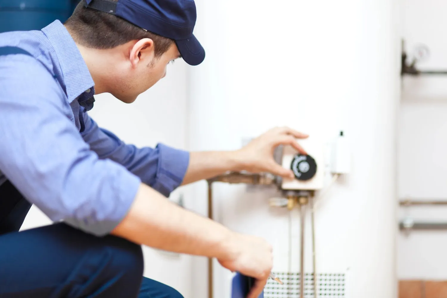 technician performing preventative maintenance on a residential water heater tank technician performing preventative maintenance on a residential water heater tank