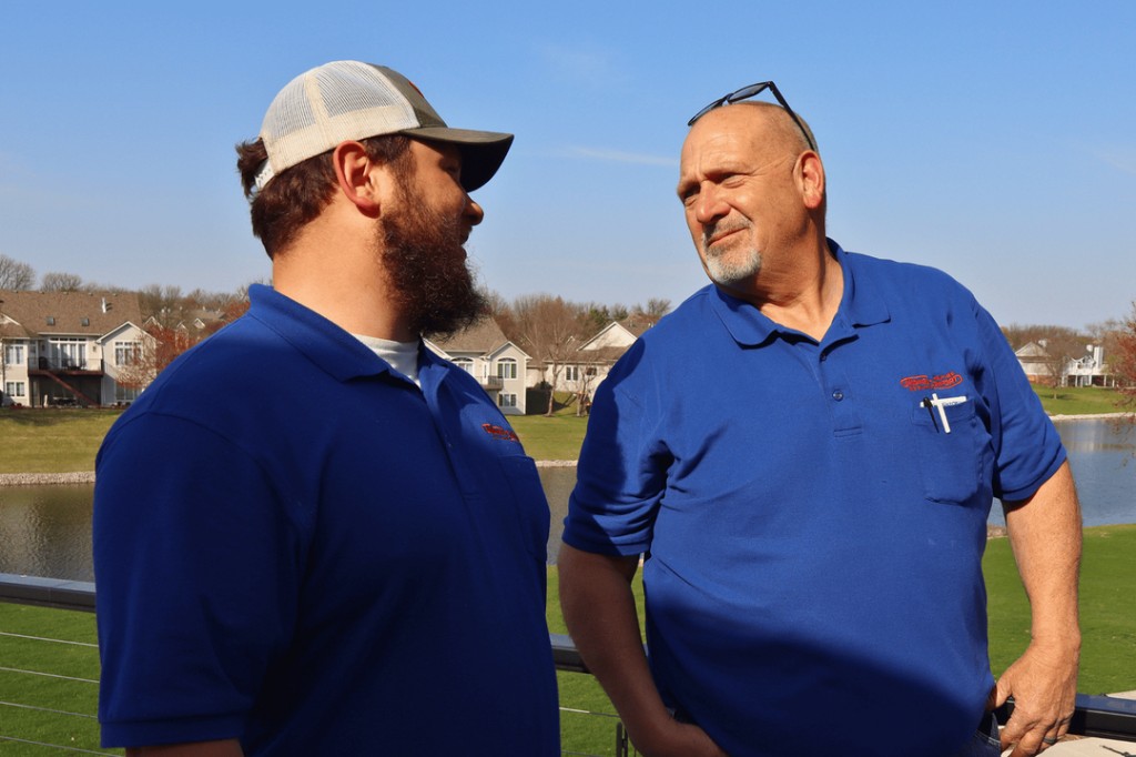 Two Midwest Comfort technicians talking in a Des Moines-metro residential neighborhood