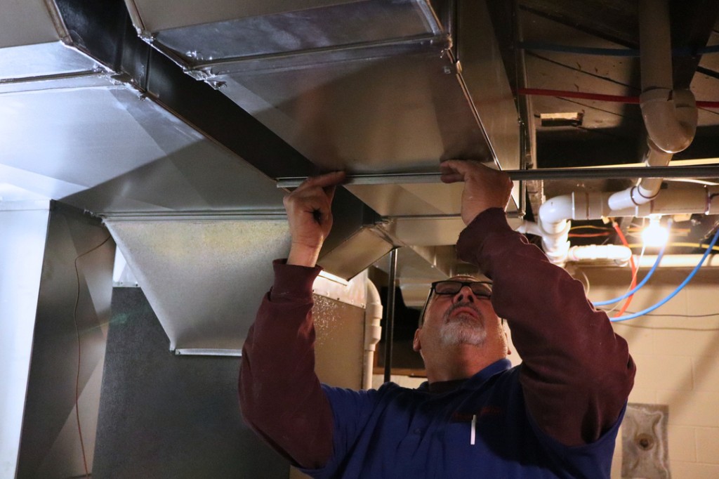 Technician adjusting residential HVAC ductwork on a Midwest Comfort project