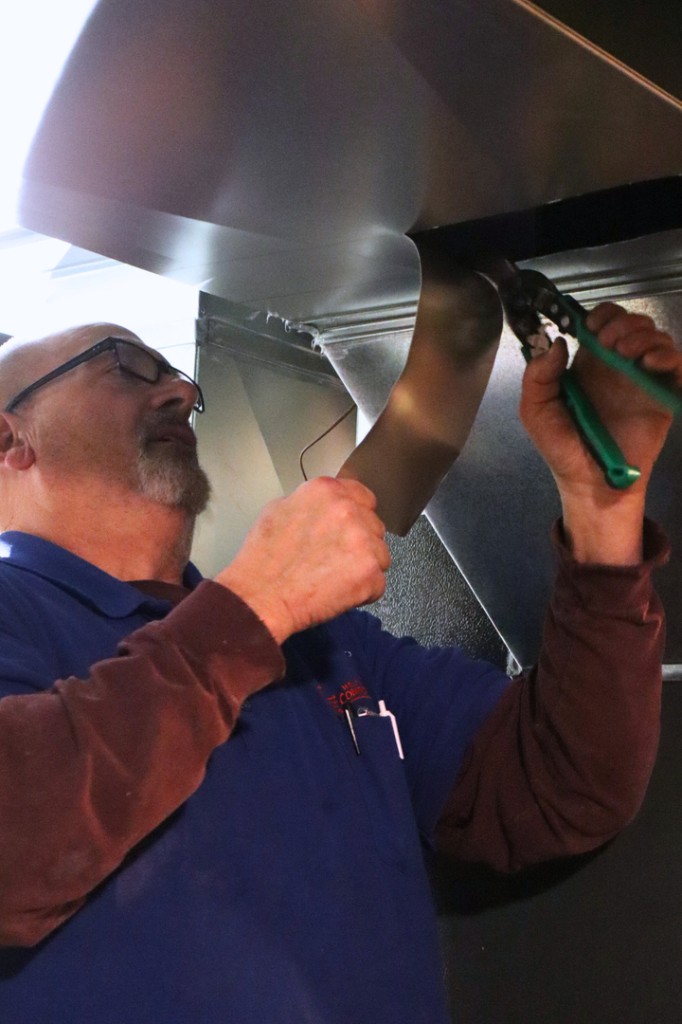 Technician installing residential ductwork on a Midwest Comfort project