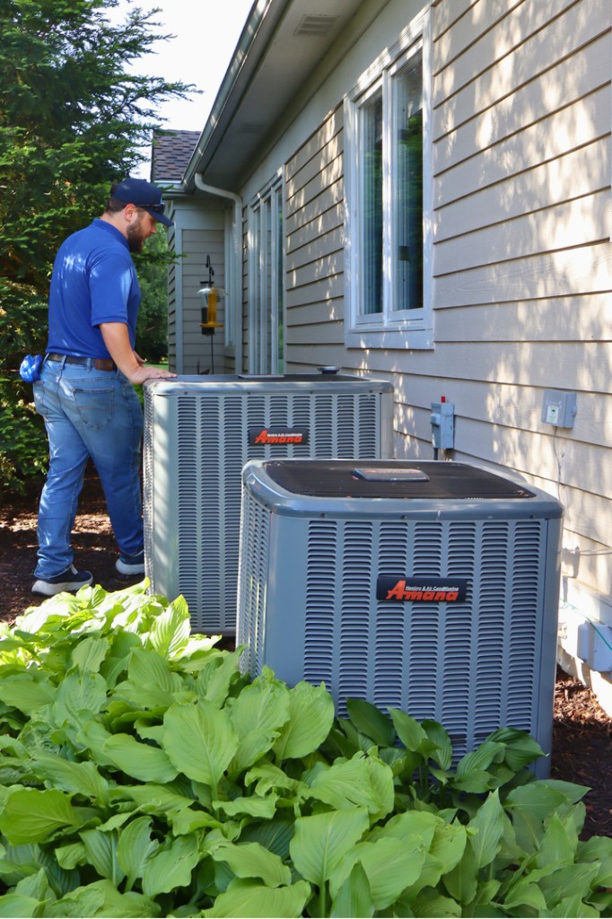 Midwest Comfort technician inspecting multiple residential outdoor AC units