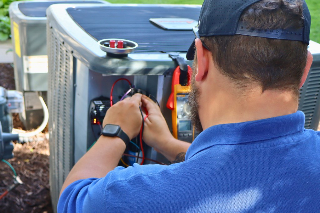 Midwest Comfort technician replacing a component on a residential AC condenser