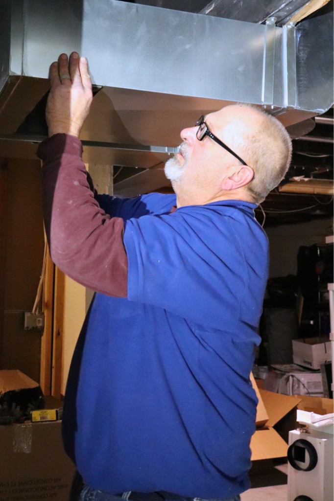 Midwest Comfort technician inspecting overhead residential ductwork